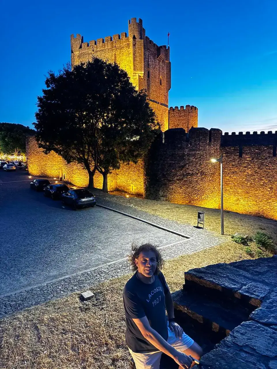 Paola sentada frente al castillo iluminado al anochecer