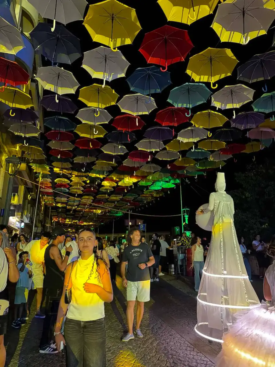 Calle con paraguas de colores iluminada durante las fiestas