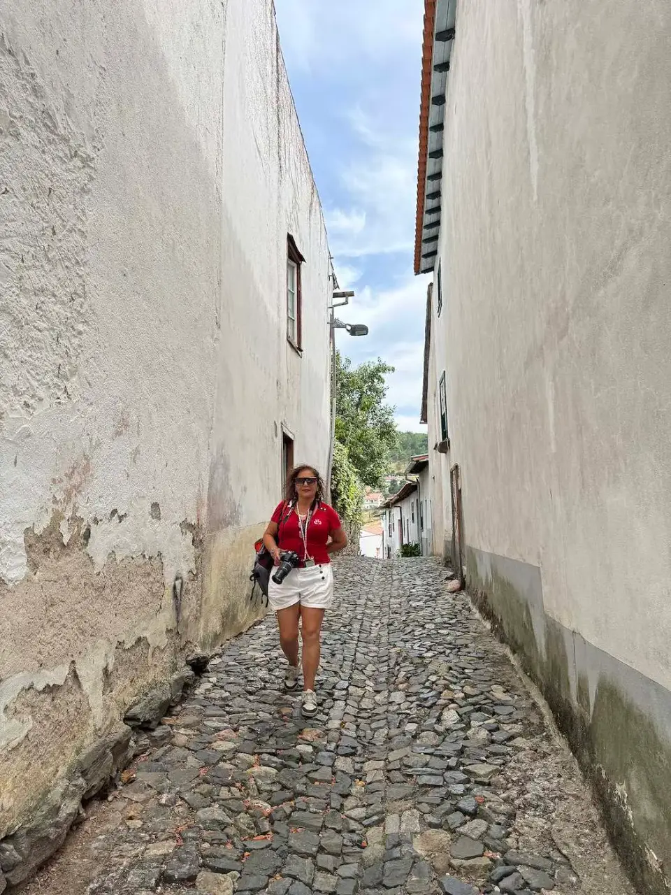 Paola caminando por una calle estrecha de casas blancas