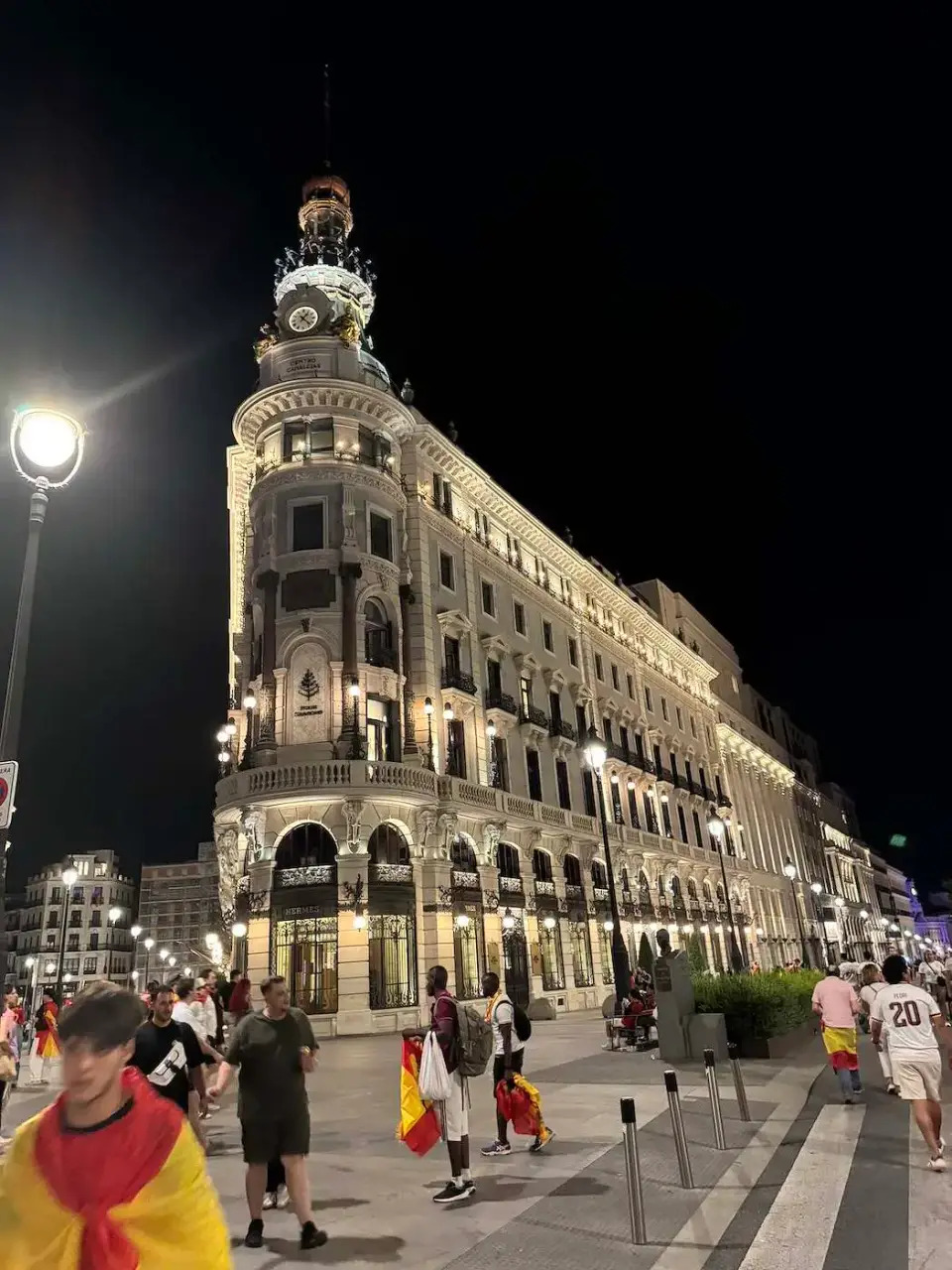 Edificio histórico iluminado de noche y aficionados con banderas