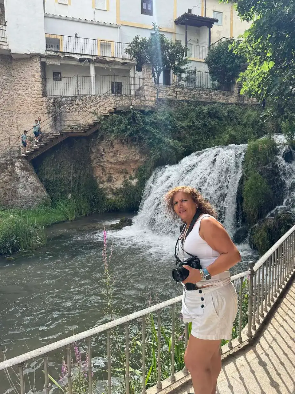 Paola junto a la cascada, con casas del pueblo encima