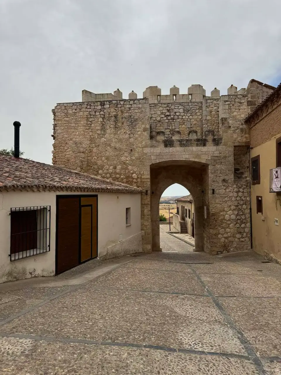 Puerta almenada de piedra al final de una calle del pueblo
