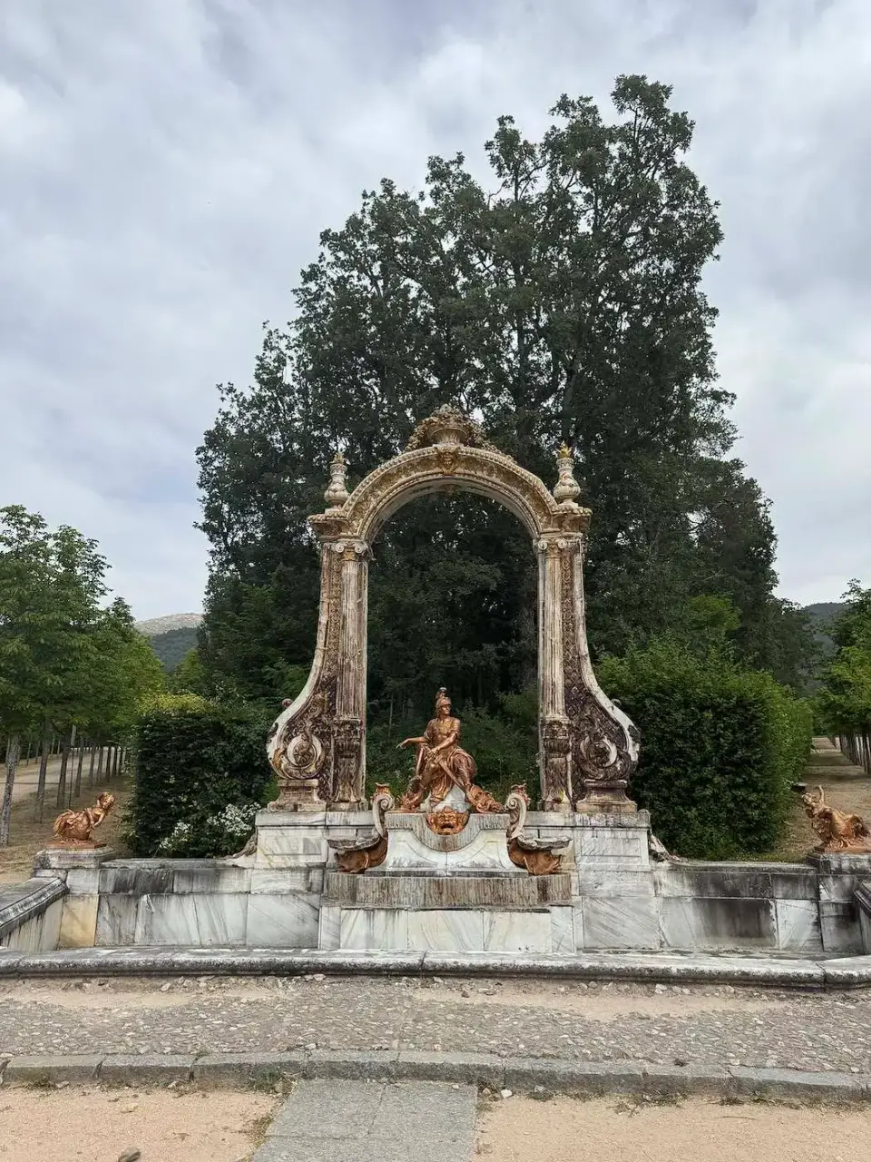 Fuente con un arco ornamental entre los árboles del jardín