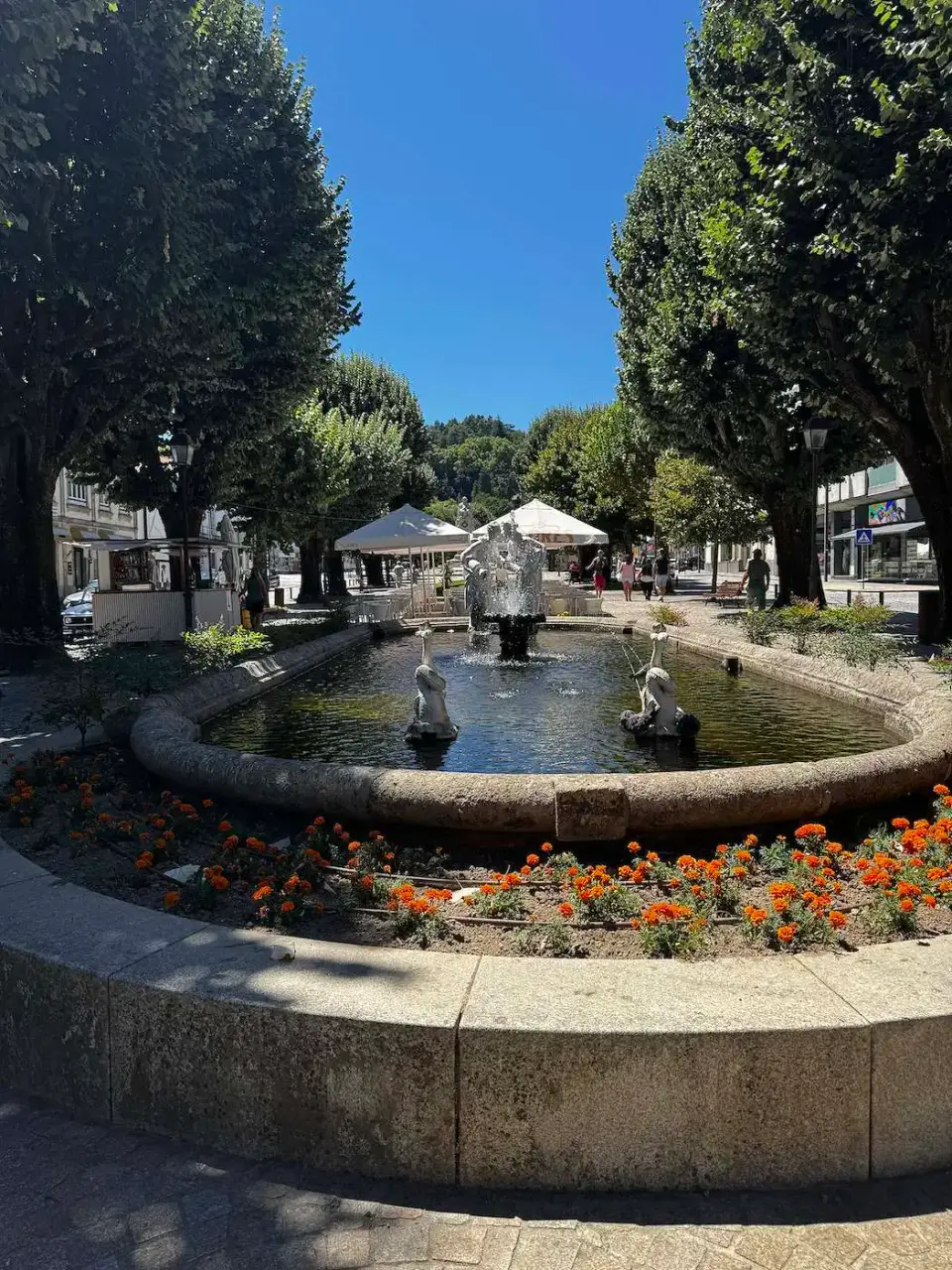 Fuente rodeada de flores en un parque arbolado