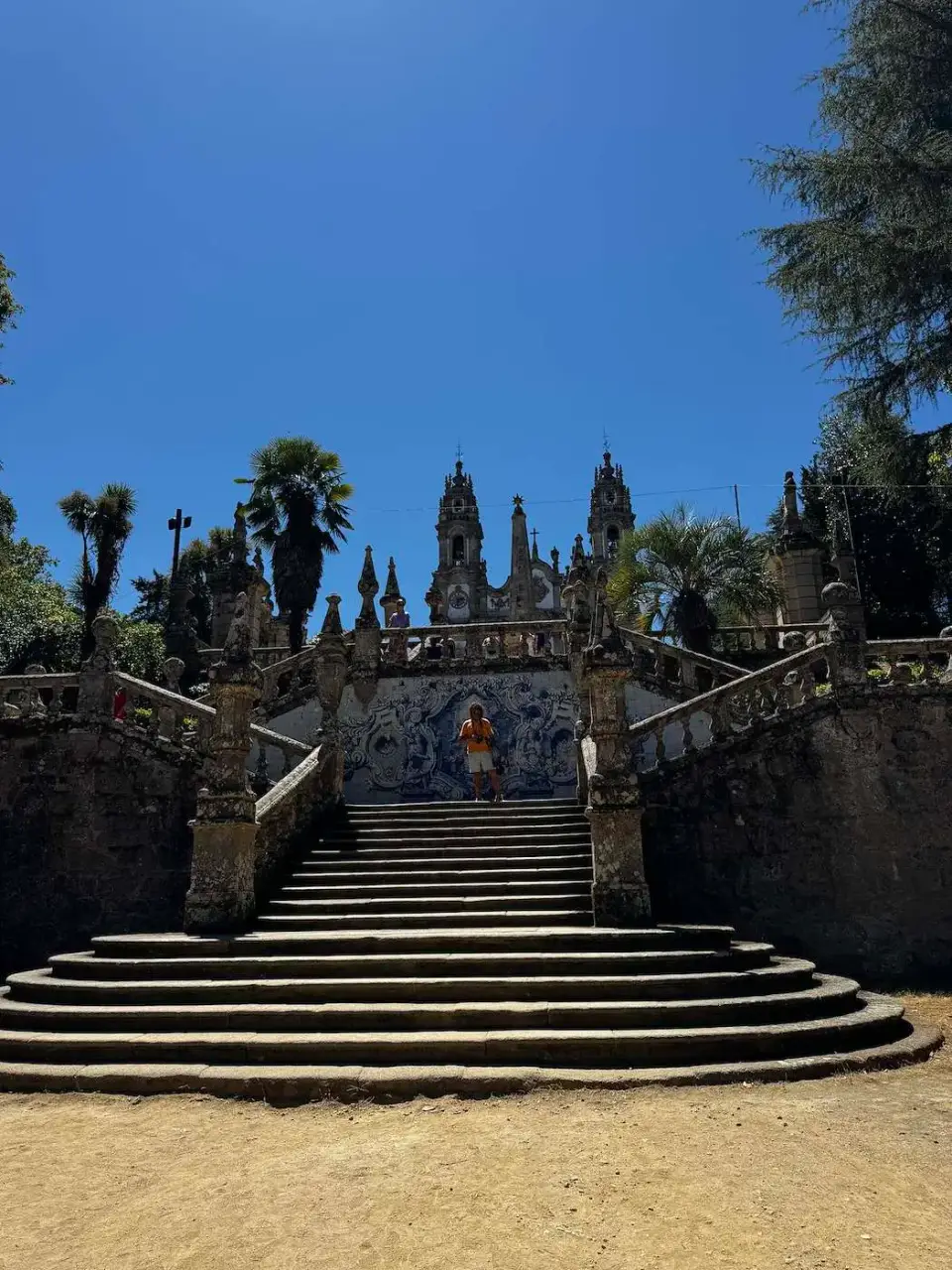 Escalinata barroca con azulejos y pináculos entre árboles