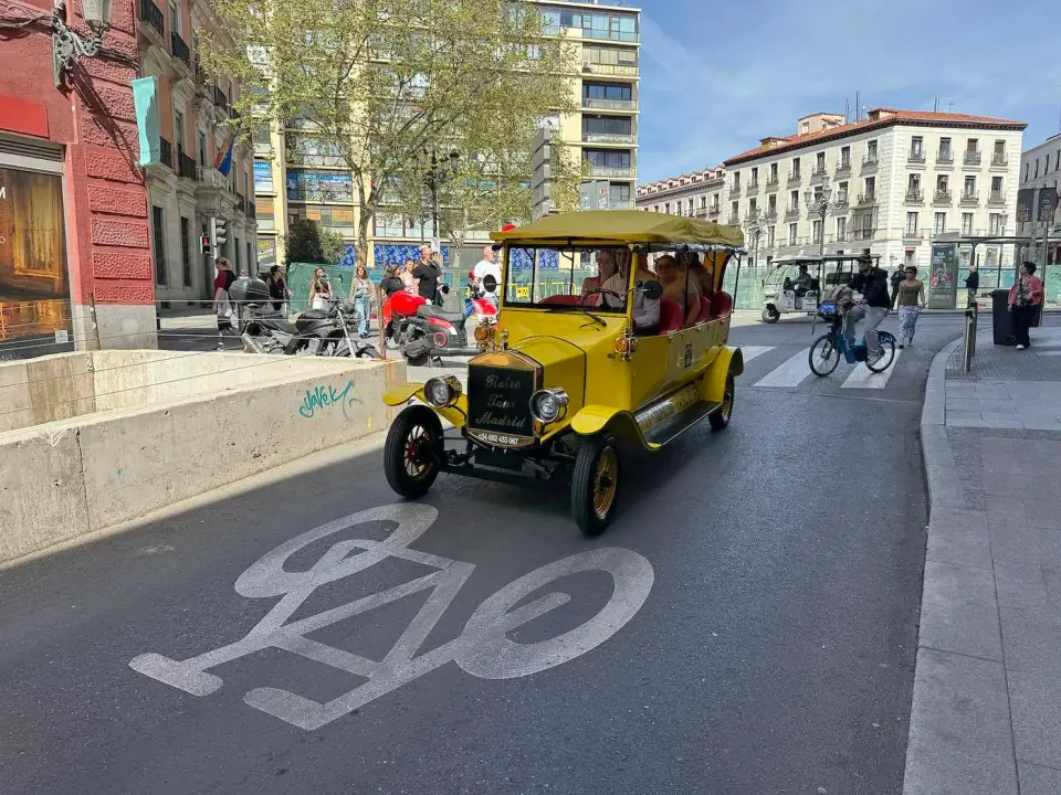 Auto antiguo amarillo recorriendo una calle de Madrid