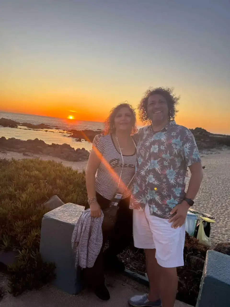 Jorge y Paola de pie frente al mar al atardecer
