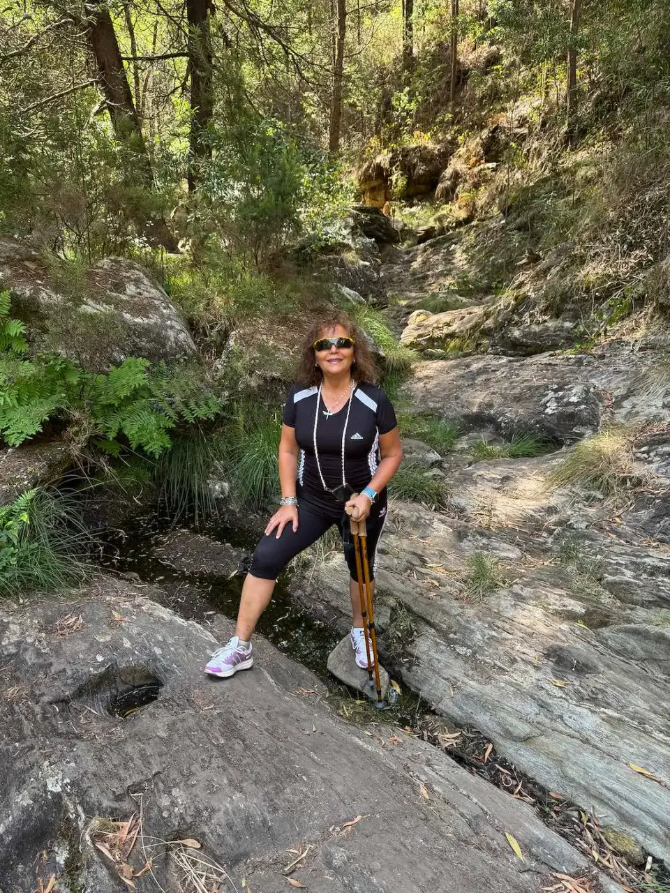 Paola posando sobre las rocas de un arroyo en el bosque