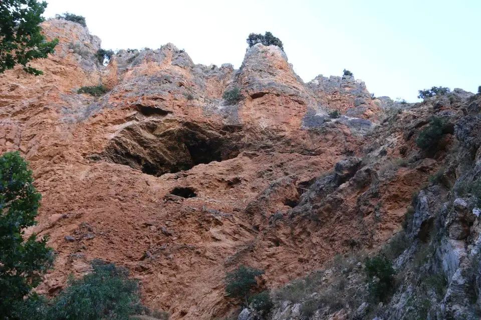 Paredes de roca rojiza con una cueva en el parque