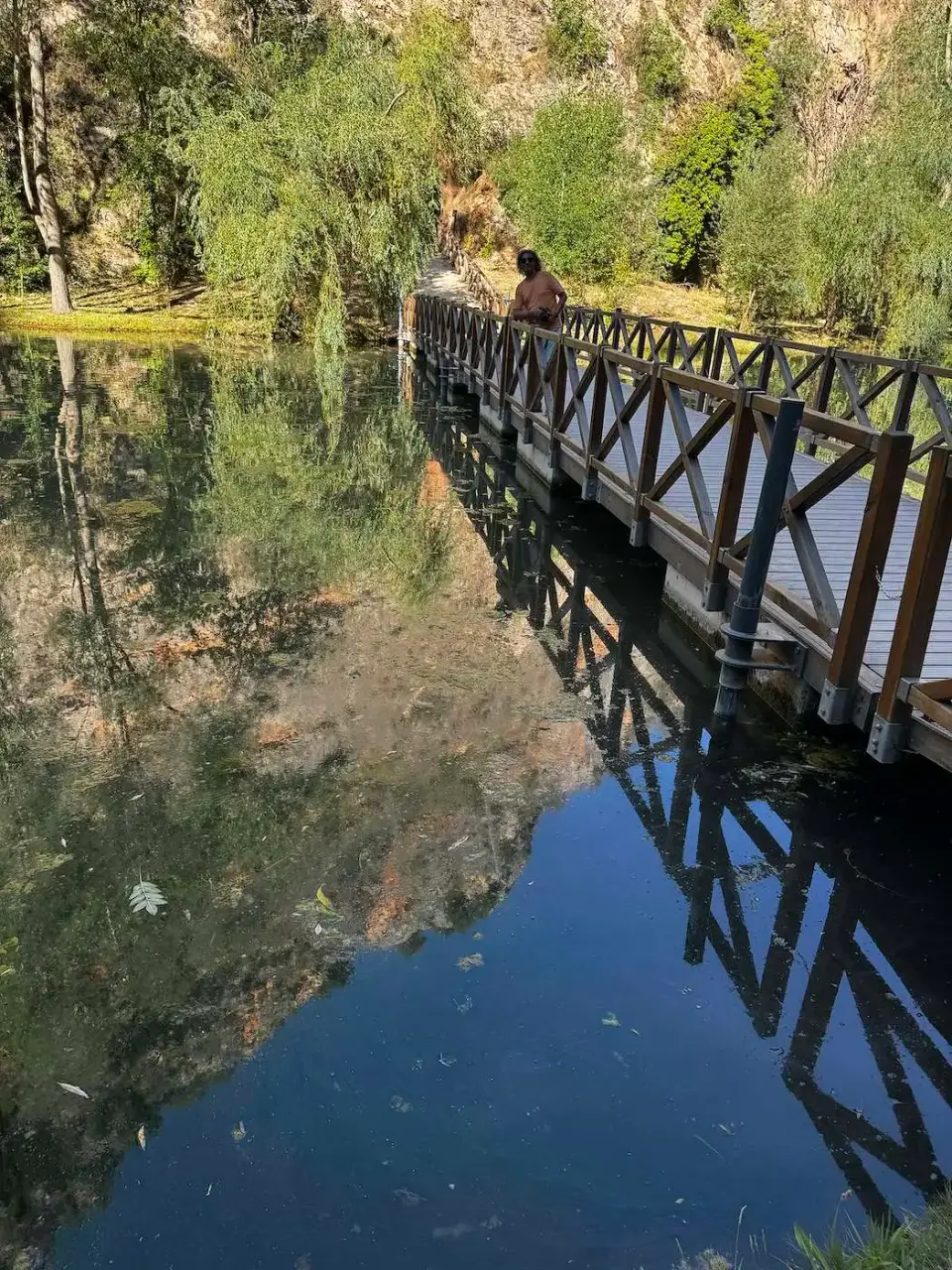 Pasarela de madera reflejada en un lago del parque