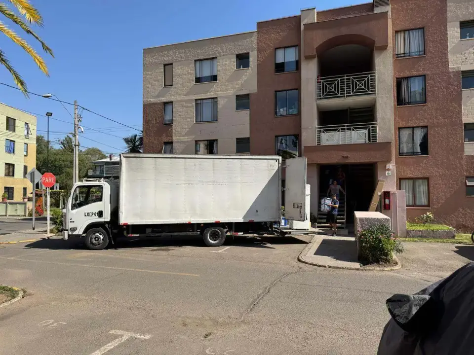 Camión de mudanza estacionado frente a un edificio de departamentos