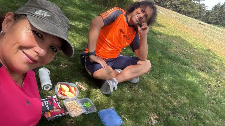 Paola y Jorge de picnic sobre el pasto en la montaña