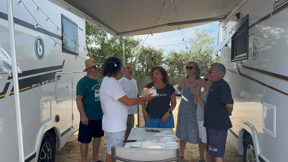 Amigos conversando bajo el toldo entre dos autocaravanas