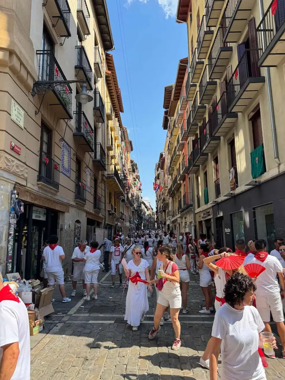 Calle del casco antiguo llena de gente vestida de blanco y rojo