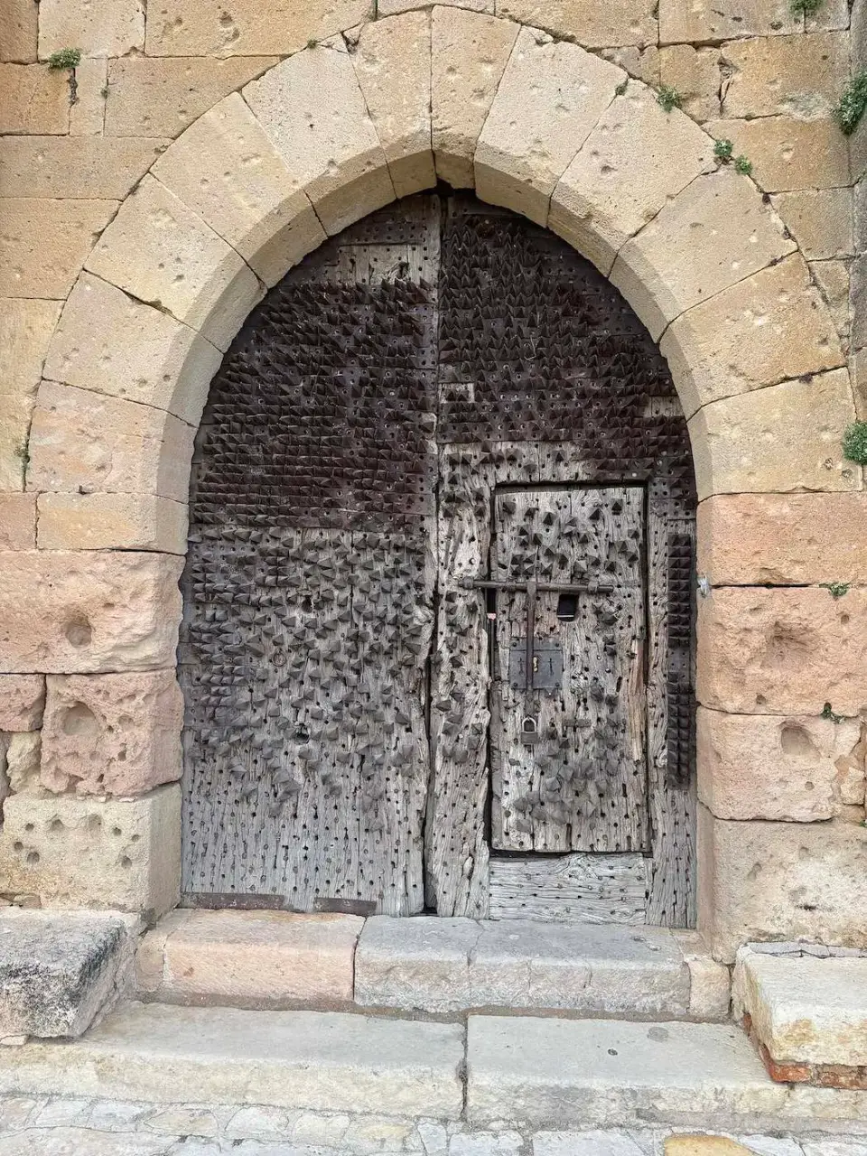 Antigua puerta de madera bajo un arco gótico de piedra