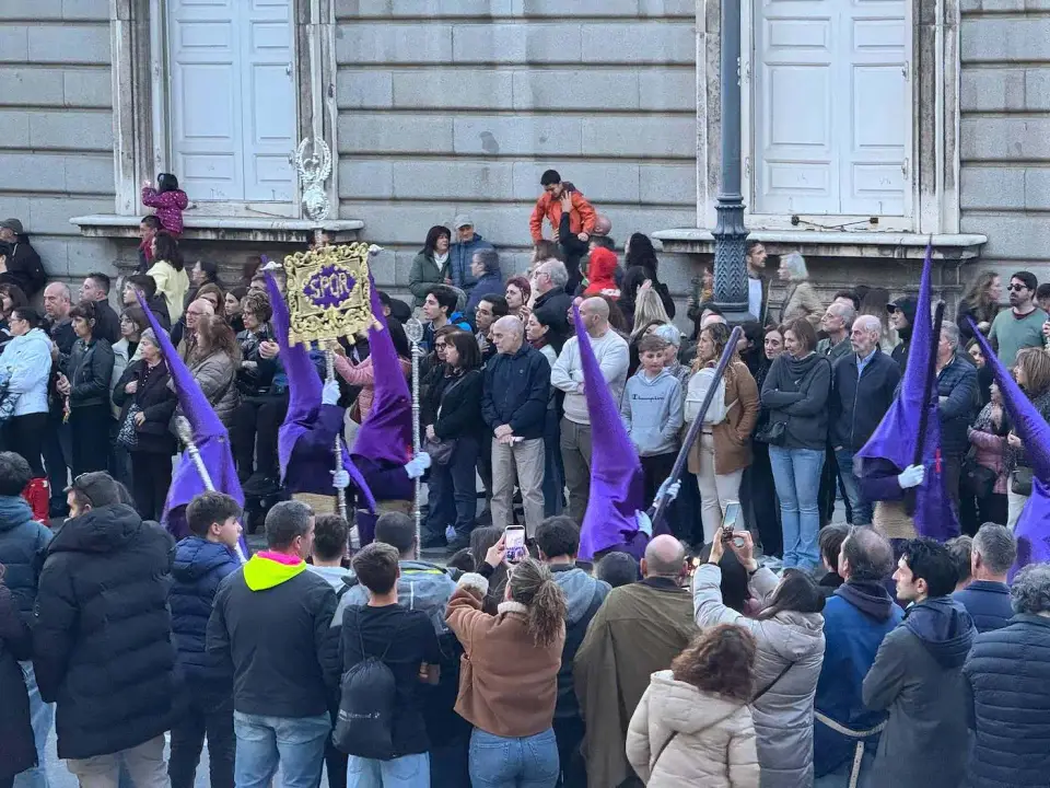 Procesión con túnicas moradas rodeada de público