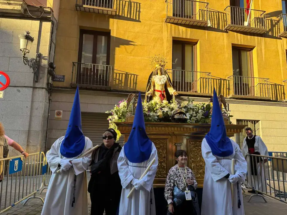 Nazarenos de capirote azul junto a un paso