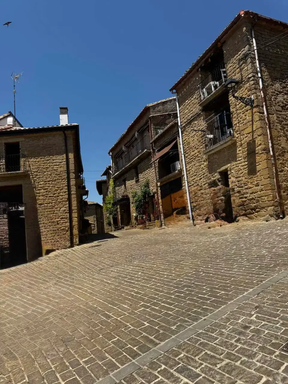 Plaza empedrada rodeada de casas de piedra en Ujué