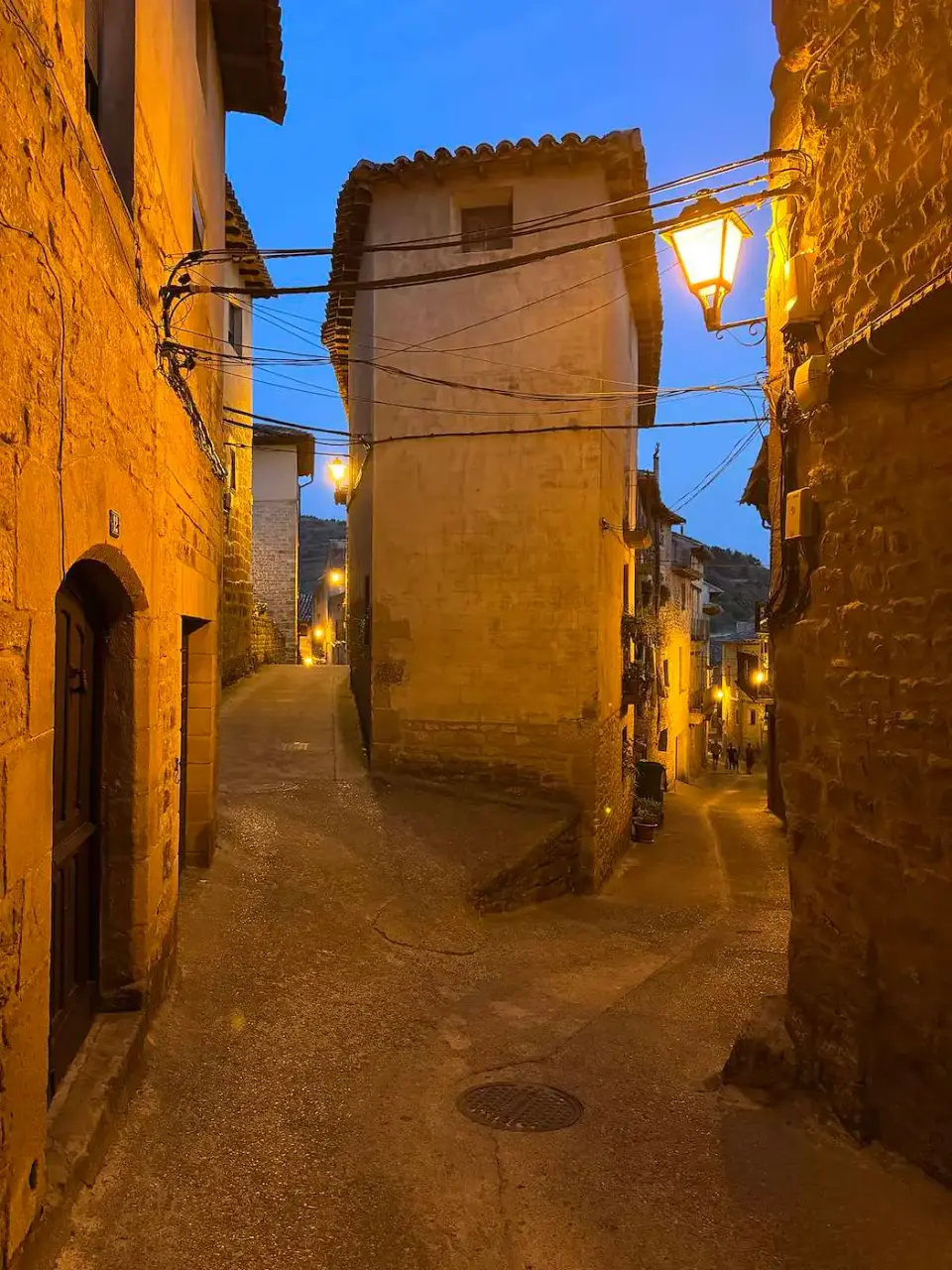 Callejuela de piedra iluminada por faroles al anochecer