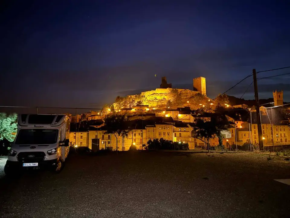 Uncastillo iluminado de noche con la autocaravana estacionada