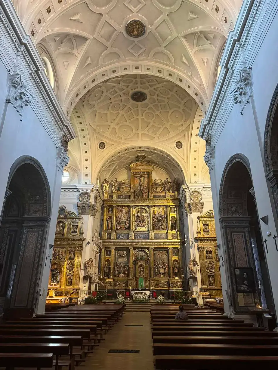 Interior blanco de una iglesia con retablo dorado