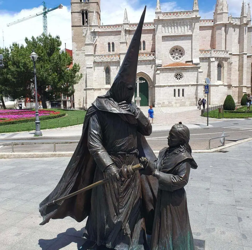 Escultura de un nazareno con capirote frente a una iglesia