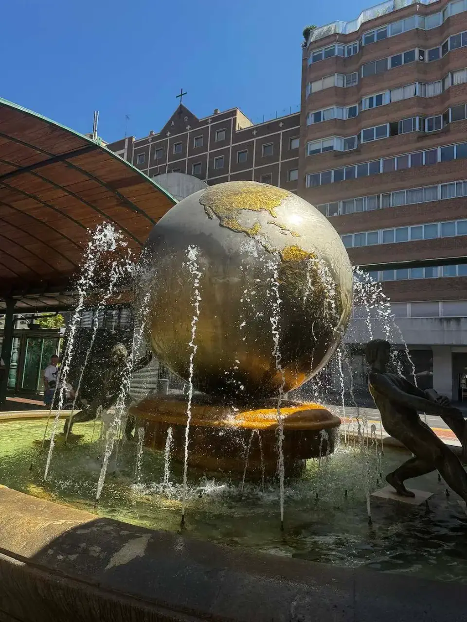 Fuente con una gran esfera dorada en la ciudad