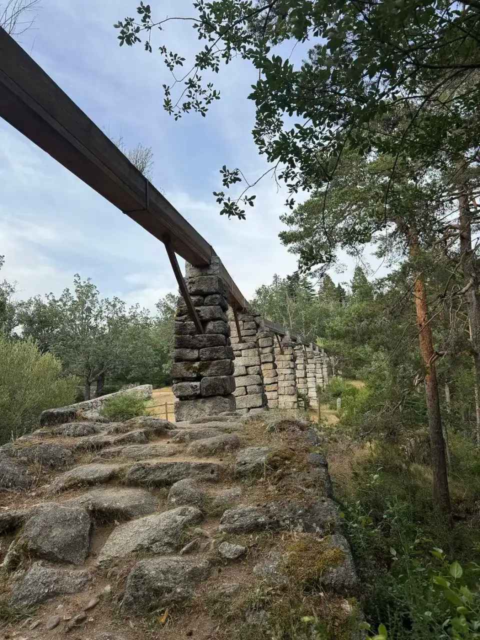 Antiguo canal de agua elevado sobre muros de piedra en el bosque