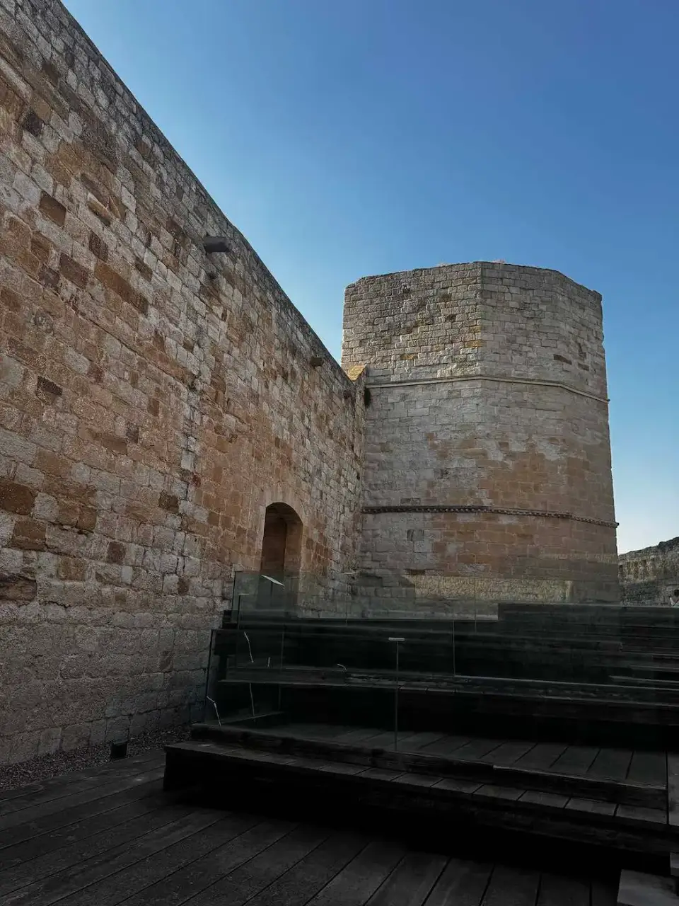 Muralla y torre redonda del castillo bajo cielo azul