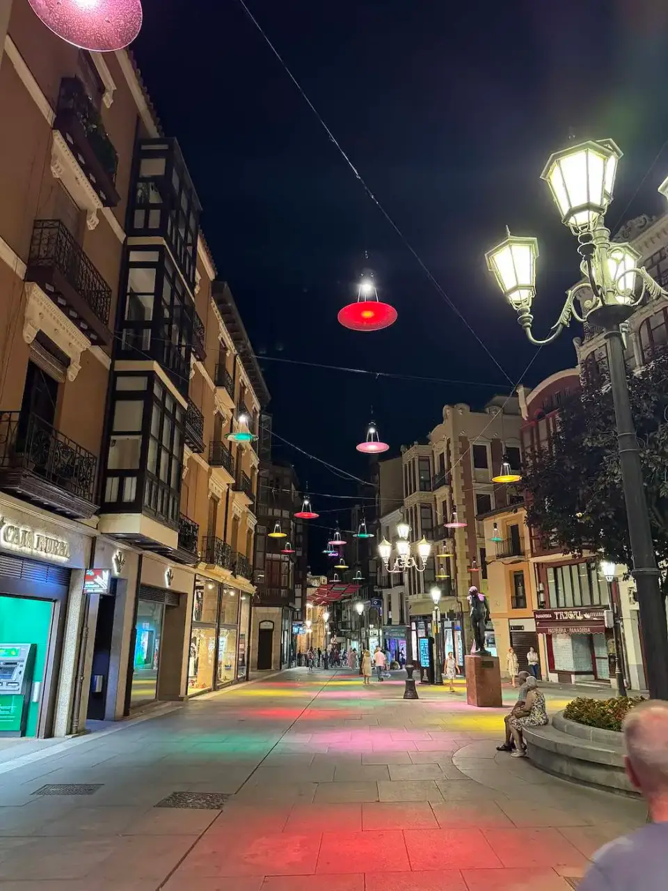 Calle comercial iluminada de noche con farolas