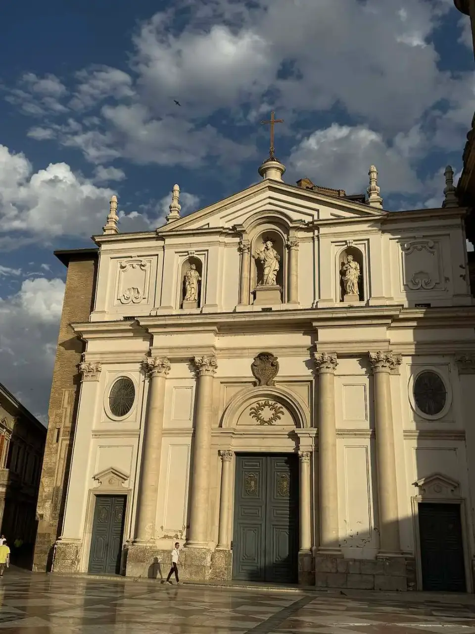 Fachada neoclásica de una iglesia bajo un cielo con nubes